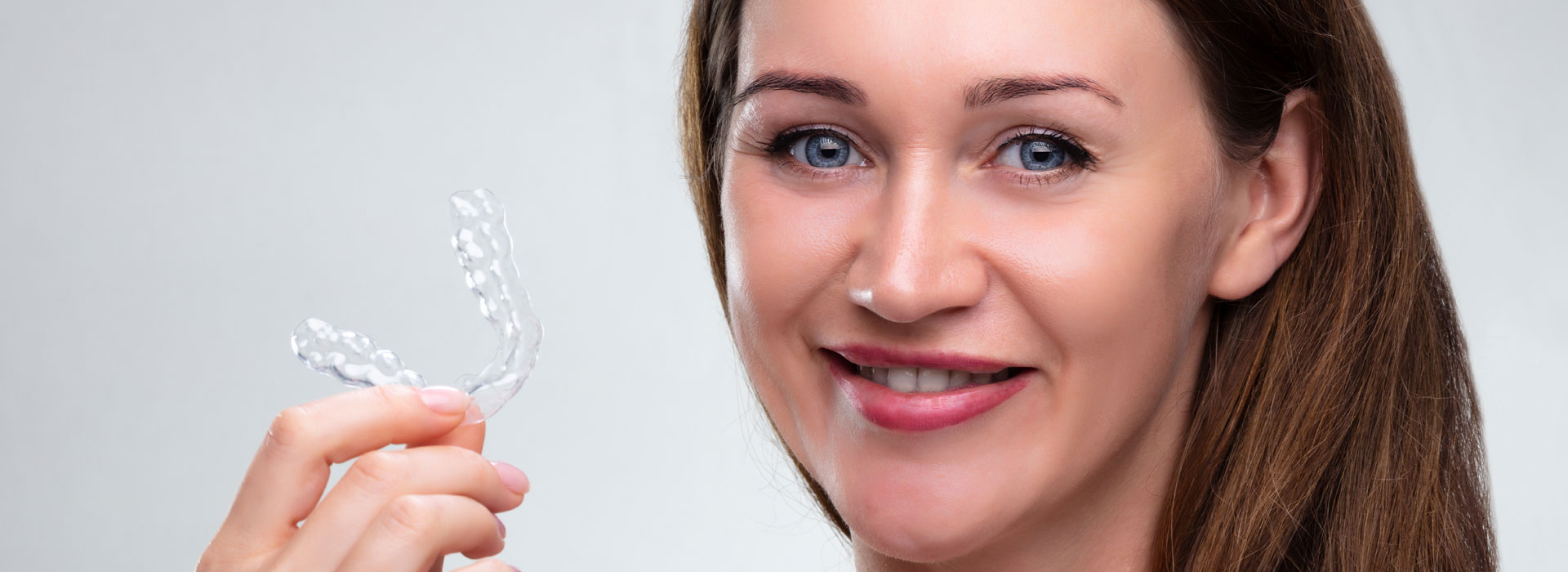 A woman holding a clear aligners